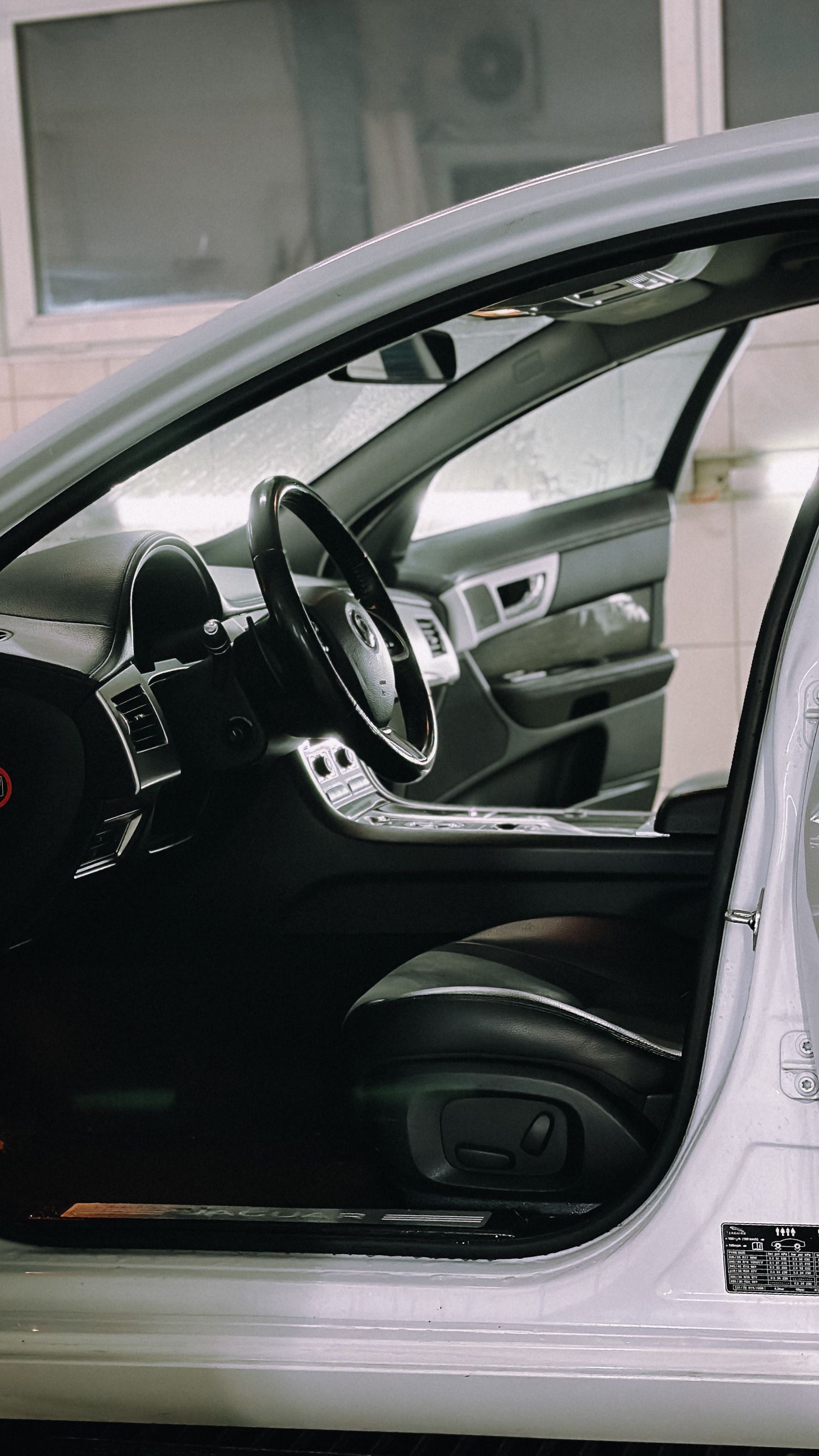 Interior of a luxury car with open door, showcasing sleek design and modern features.