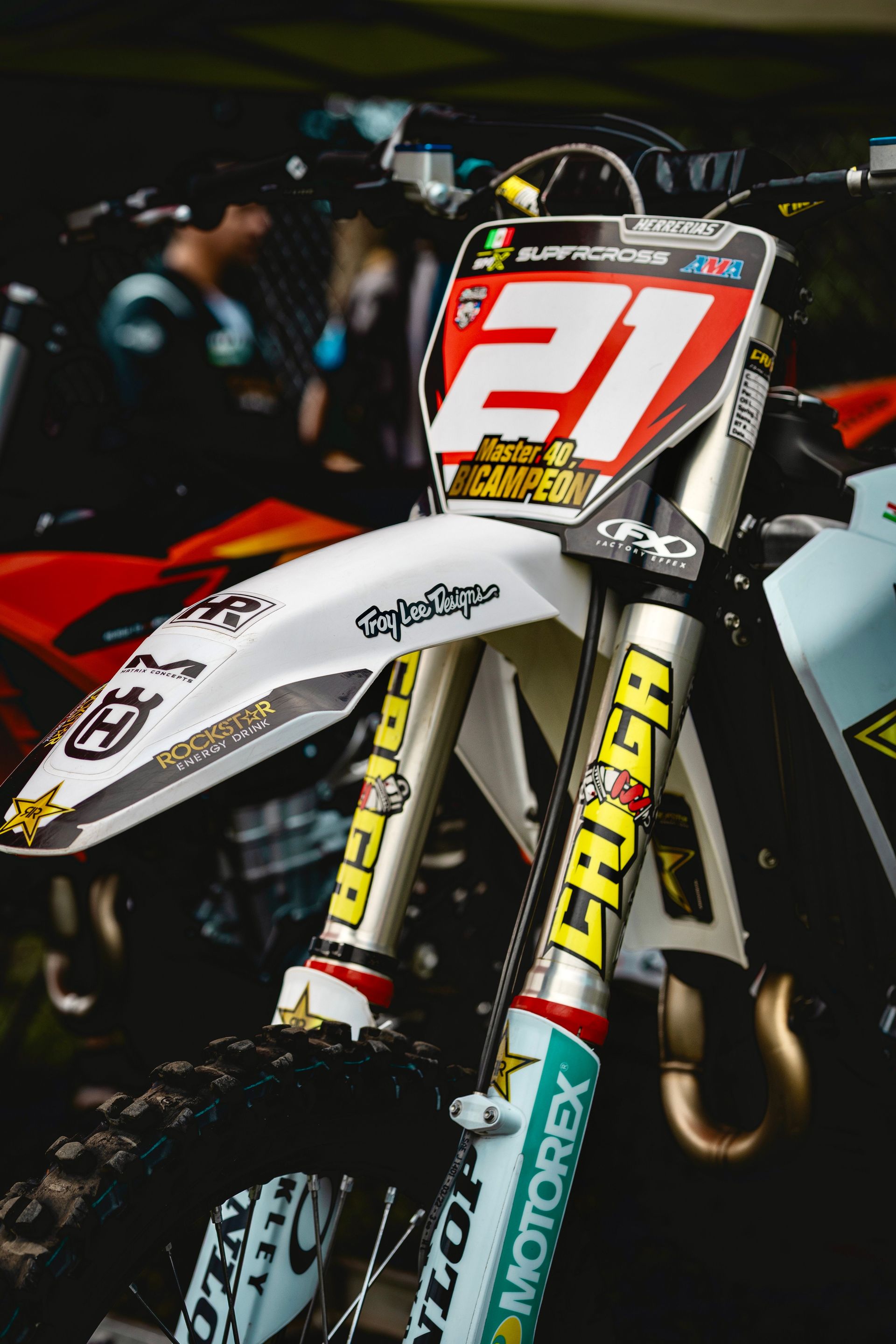 Detailed view of a dirt bike at a motocross competition with vibrant graphics.