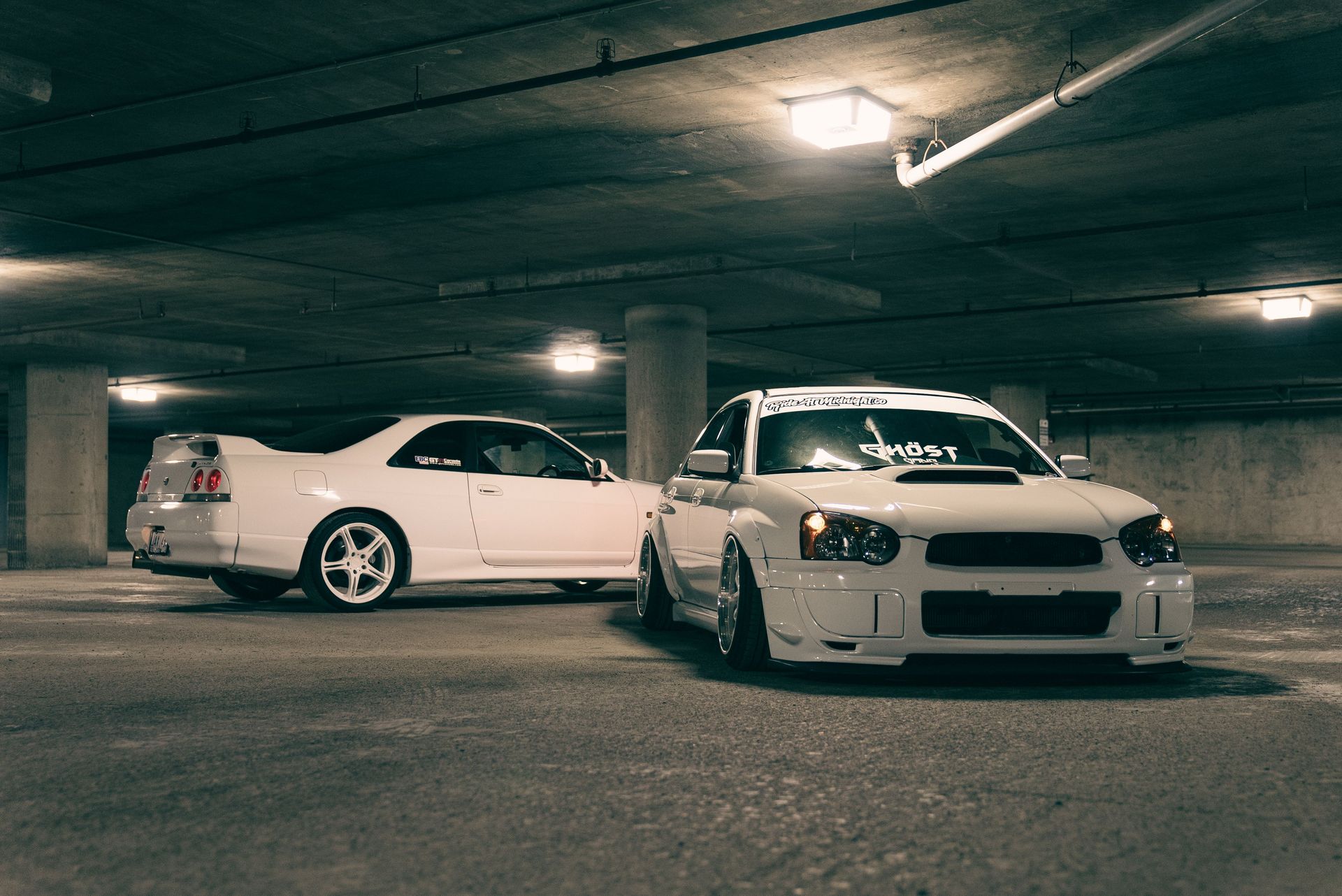 An atmospheric shot of sleek white cars parked in a dimly lit underground garage.